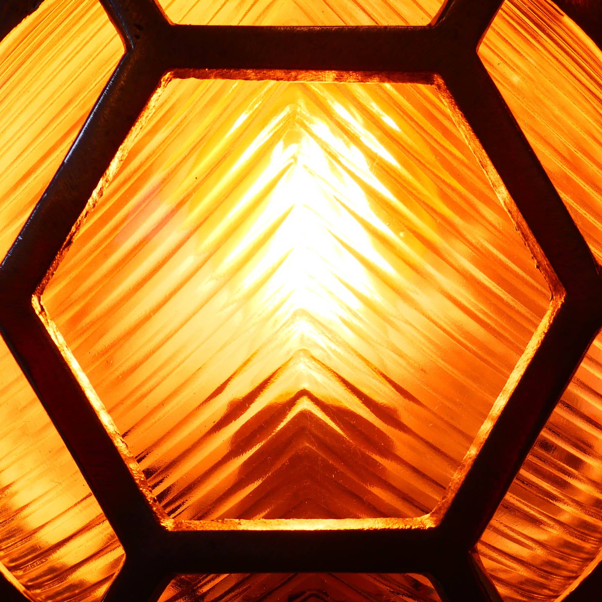 Old cast aluminum wall light with hexagonal grid and wide streaked glass.