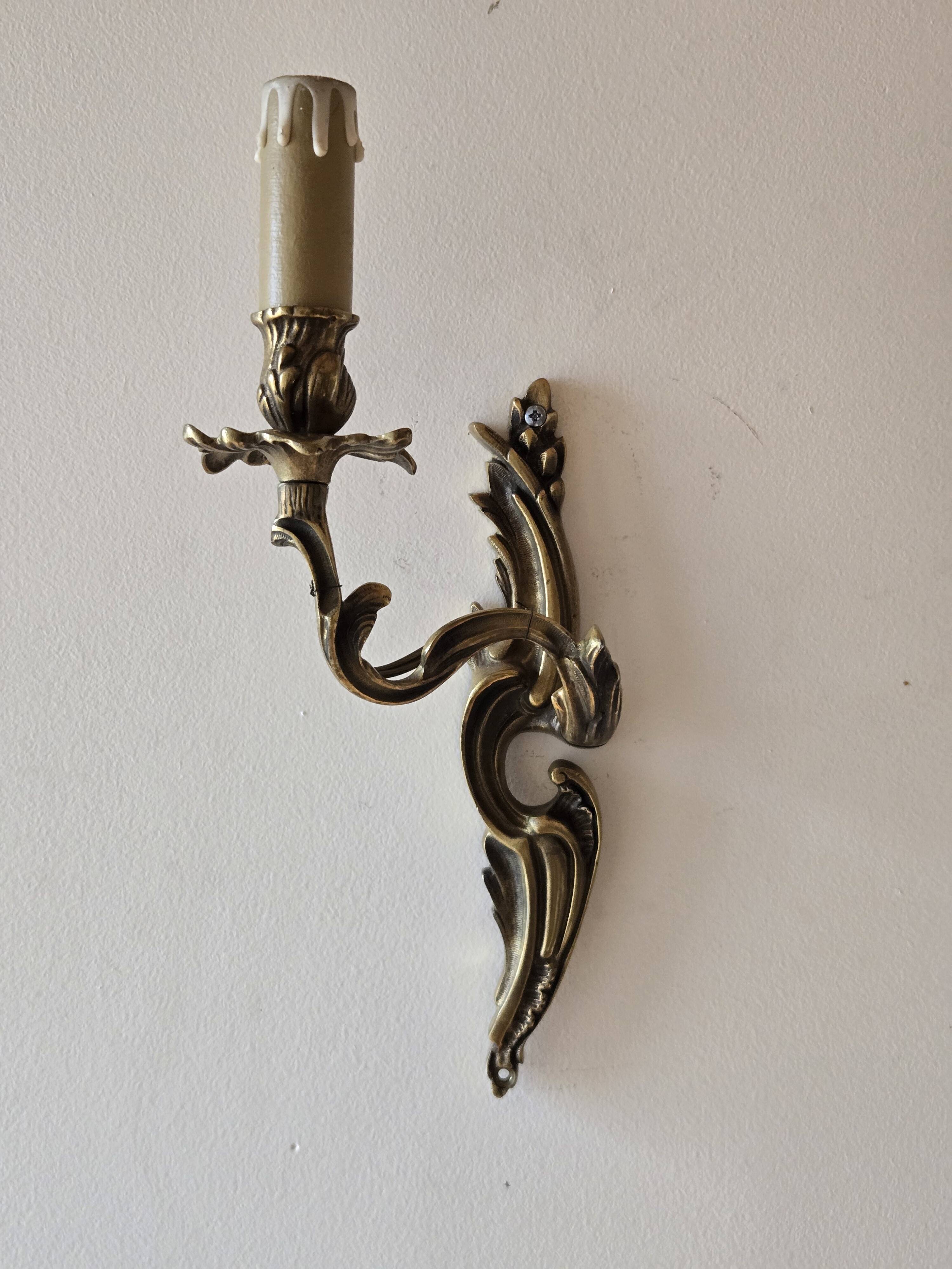 Pair of symmetrical gold wall sconces in baroque style made of bronze.