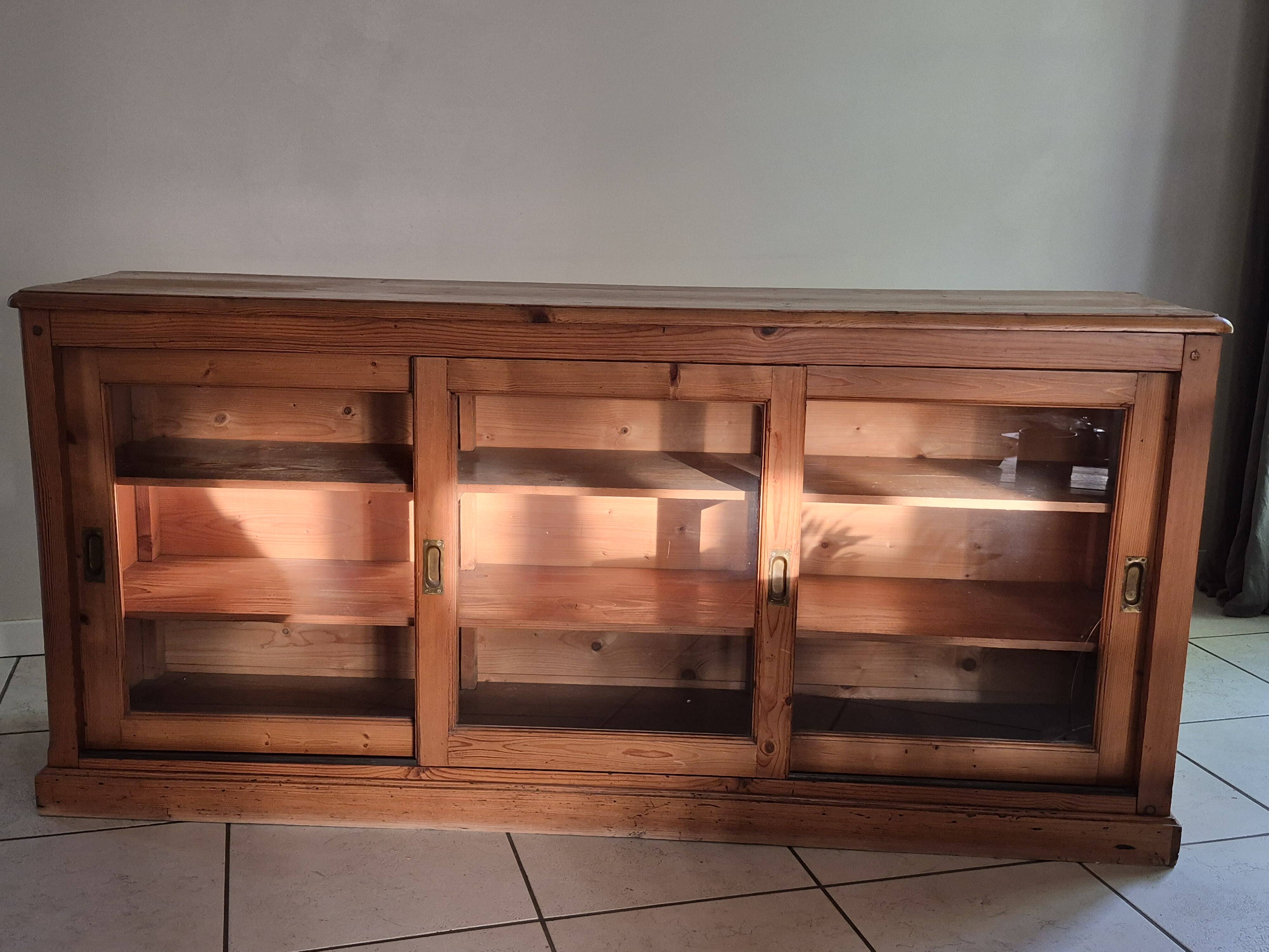 Antique wooden sideboard with three sliding glass doors.