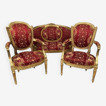 Partie de salon de style Louis XVI en bois doré. Canapé corbeille et paire de fauteuils