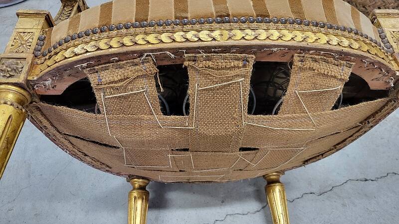 A pair of gilded wooden armchairs in the Louis XVI style.