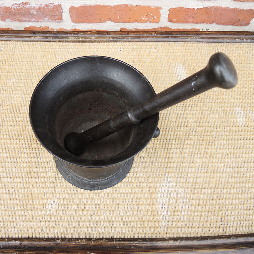 Ancient large mortar and pestle of a black cast iron apothecary.