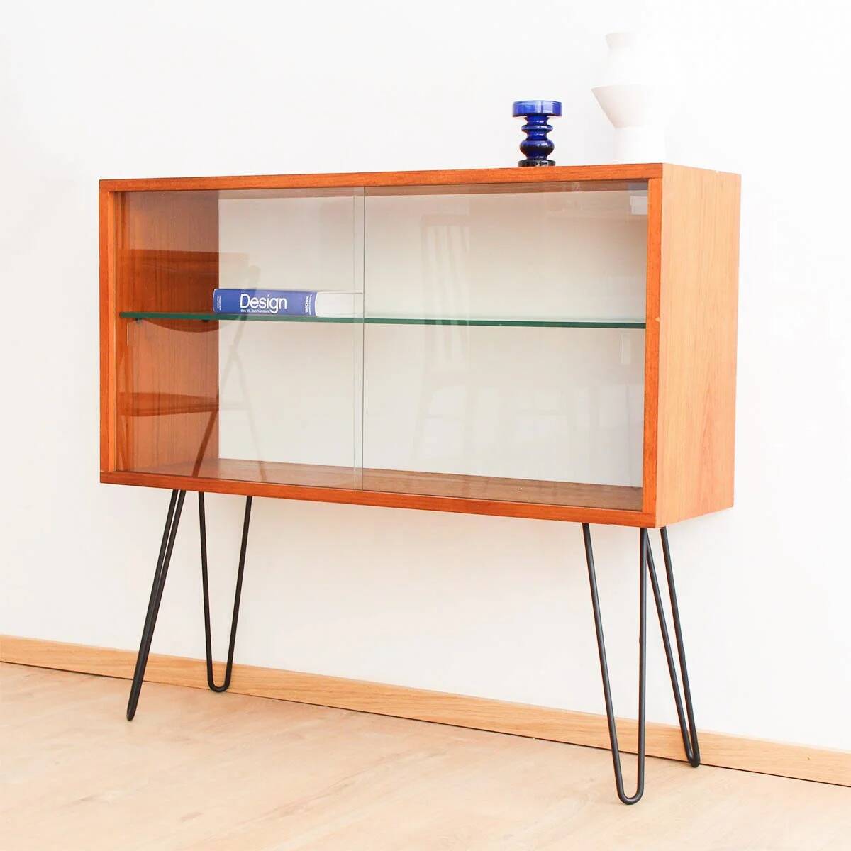 Teak display cabinet with black hairpin legs.