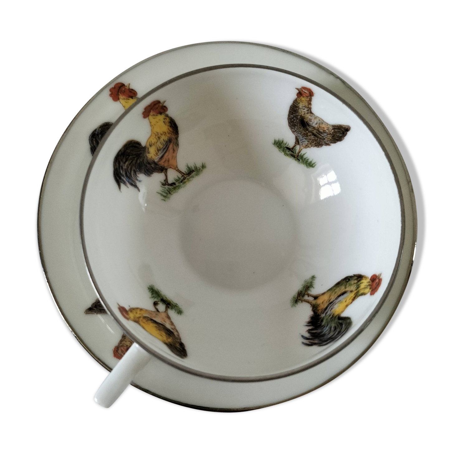 Cup and saucer in porcelain decorated with roosters and hens.