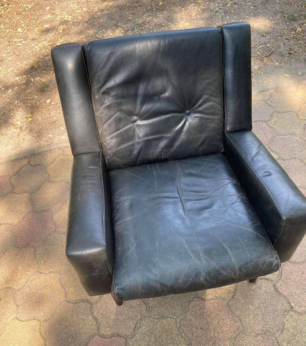 Mid-Century Italian armchair from the 1960s in black leather and dark wood, with a tufted backrest.