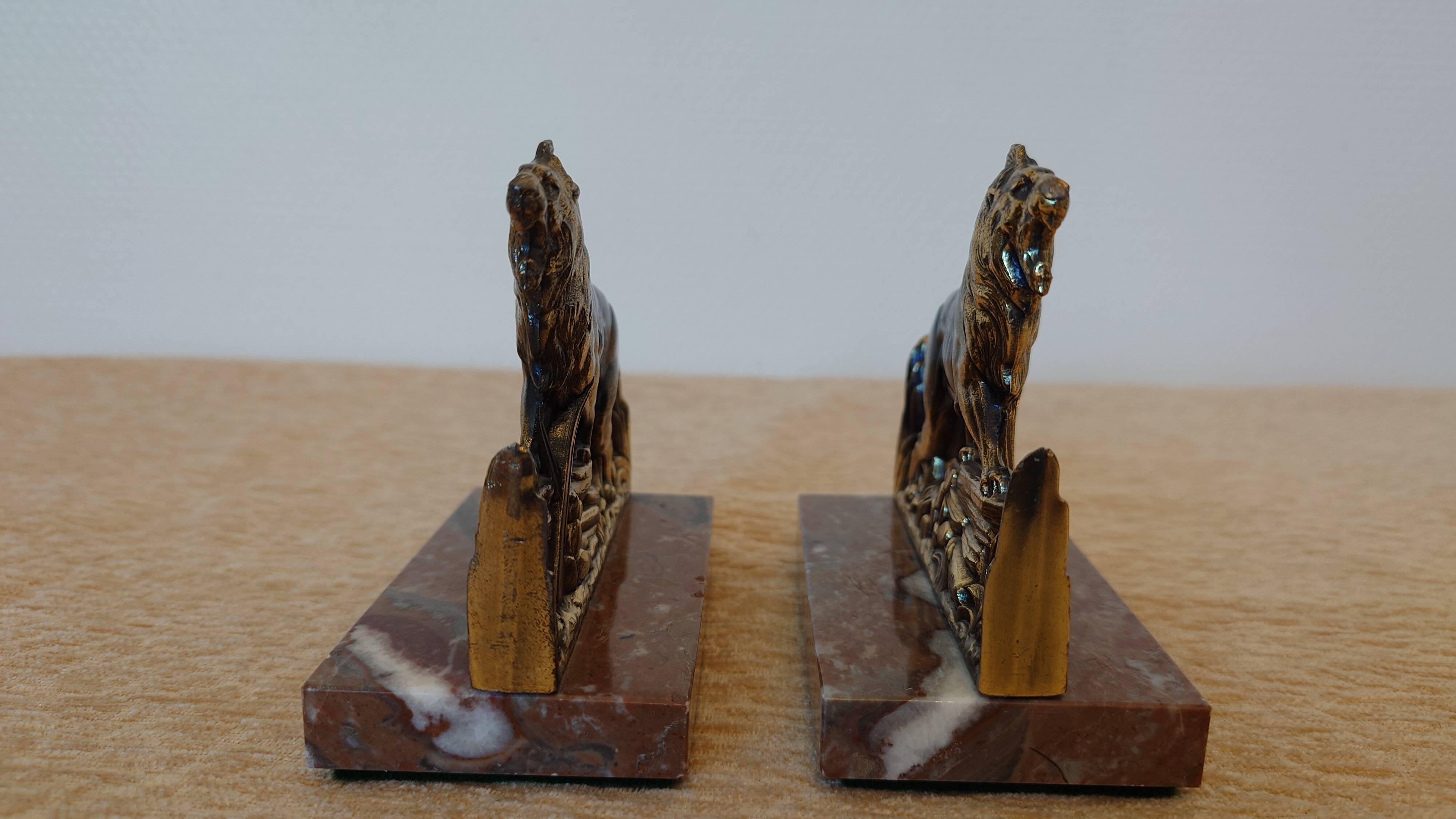 Small roaring lion bookends in patinated metal on a marble base.