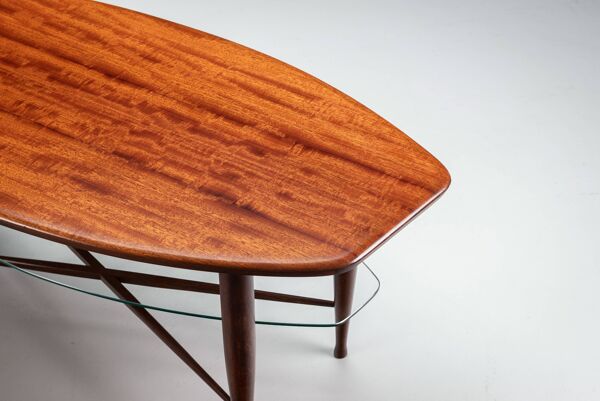 Table basse asymétrique avec rangement en verre et détails de pieds en croix.