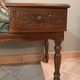 Antique carved wooden bench with green upholstered seat and backrest.