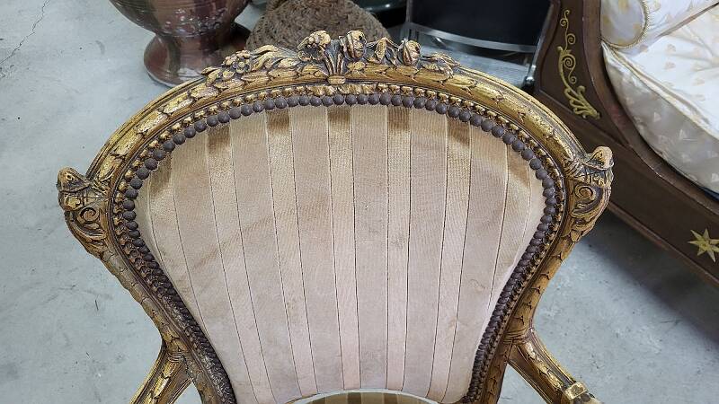 A pair of gilded wooden armchairs in the Louis XVI style.