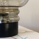 Sciolari table lamp with smoked glass globe and black plastic base.