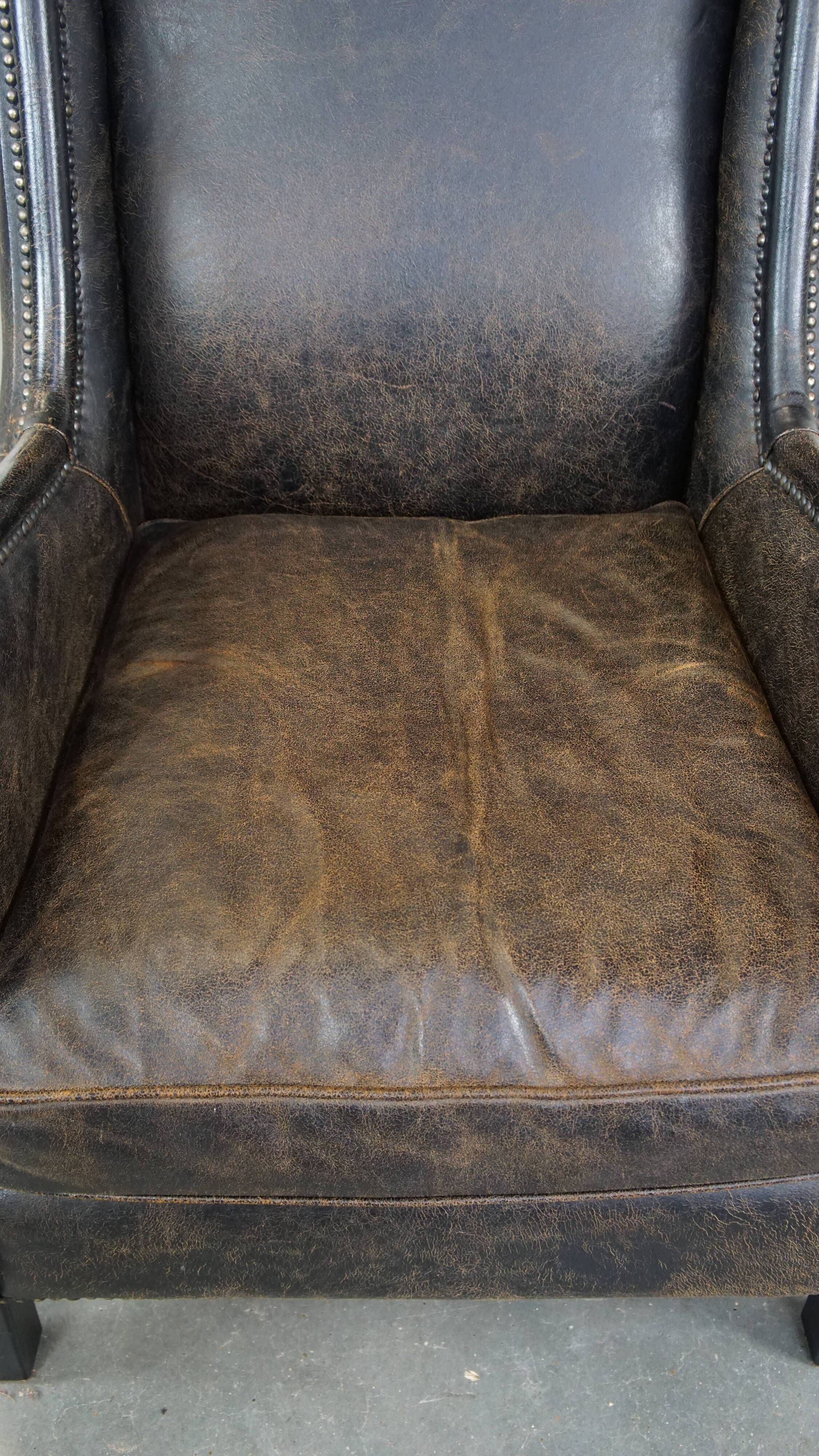 Black cow leather armchair finished with decorative nails, industrial style