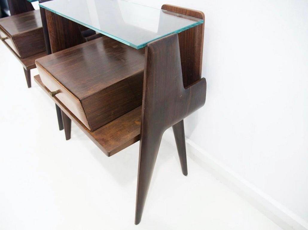 Pair of modernist Italian bedside tables in wood with a glass top.