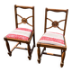 Pair of antique walnut chairs with rose design and red striped cushions.