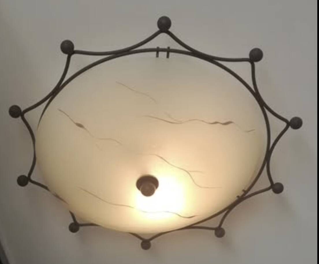 Round ceiling light with a wrought iron frame.