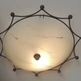 Round ceiling light with a wrought iron frame.