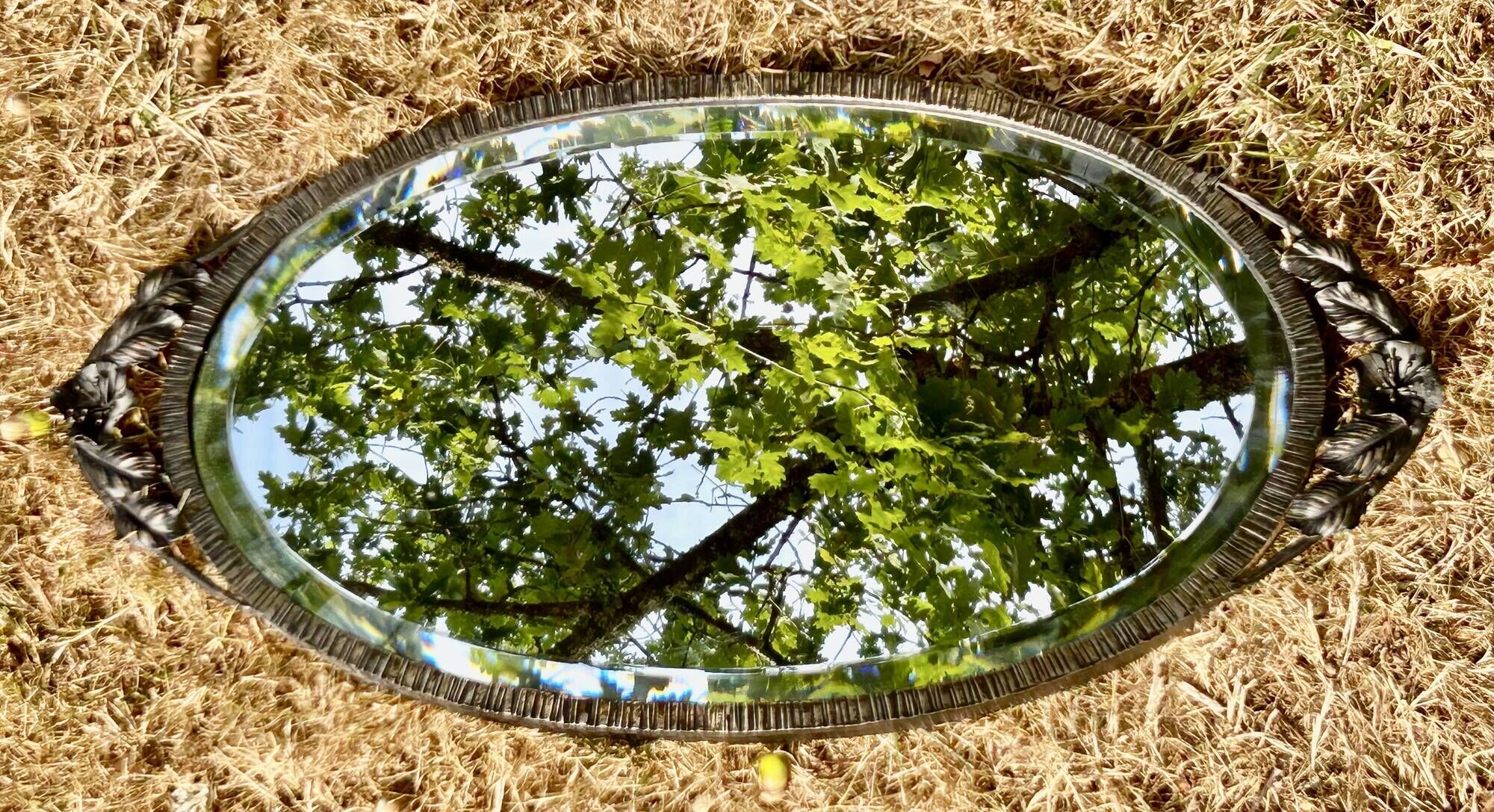 Bevelled oval mirror, richly crafted Art Deco wrought iron.