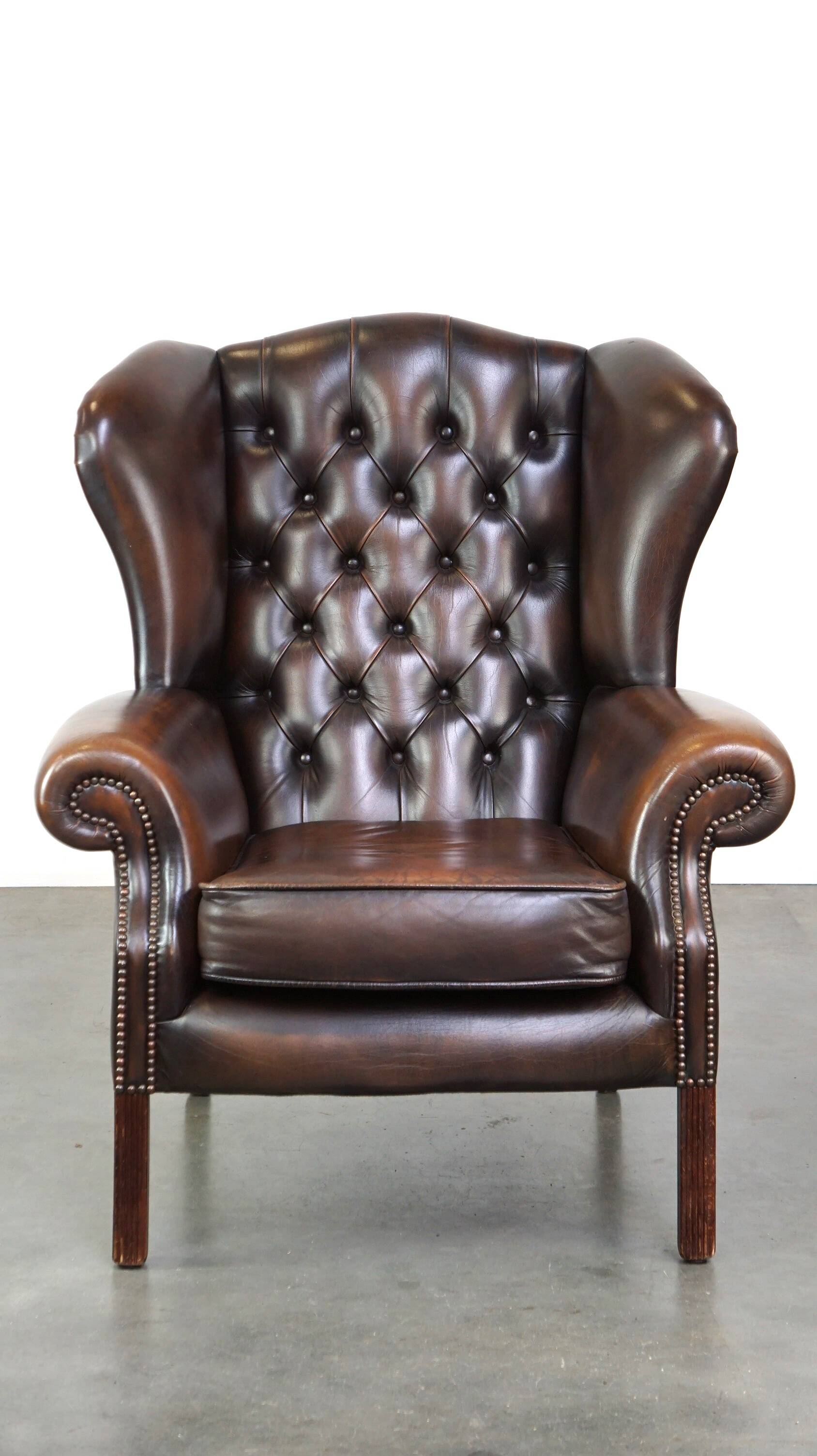 Chesterfield wing chair in dark brown leather with a luxurious appearance