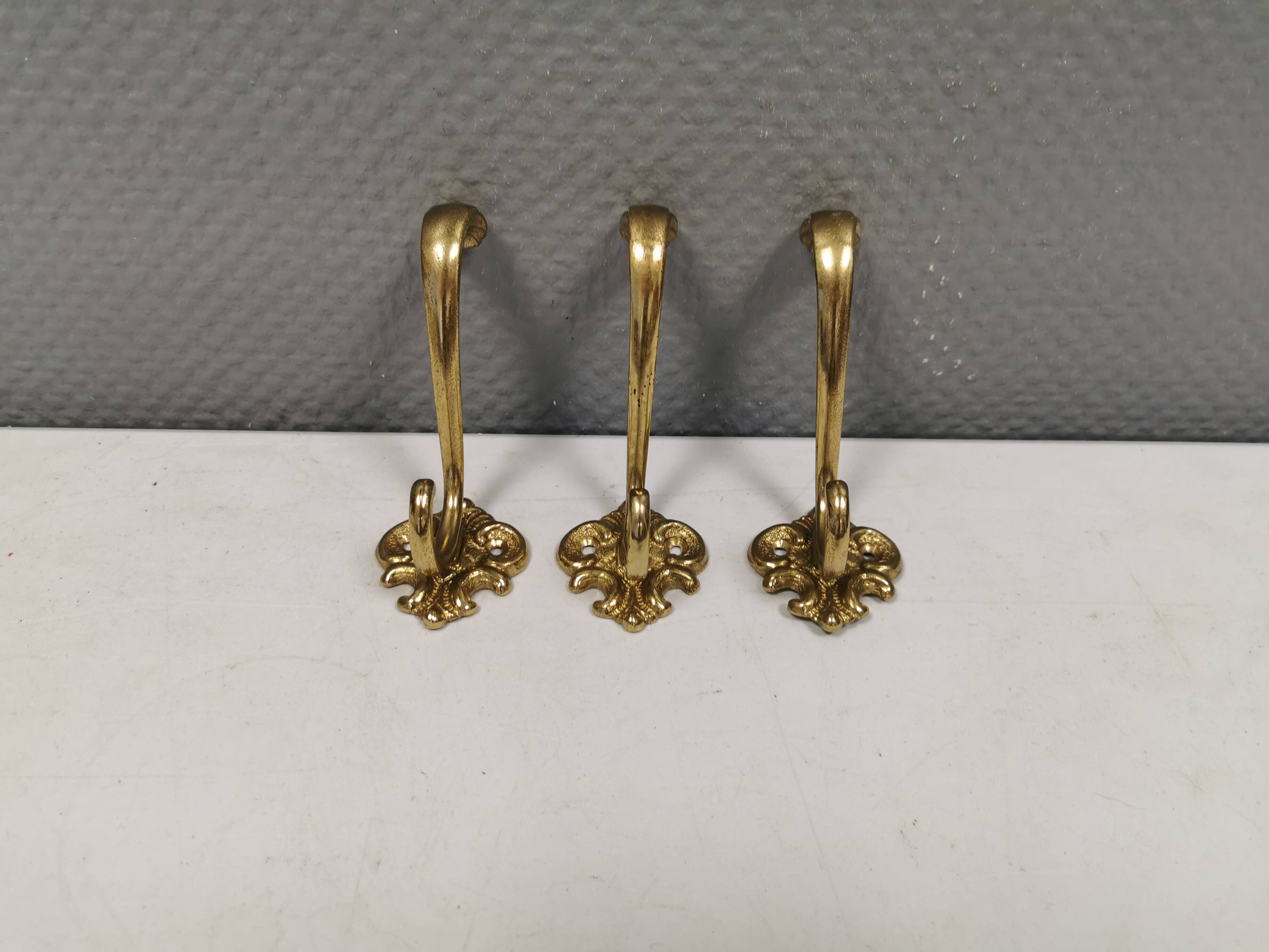 Three old and beautiful brass hooks with decorative motifs