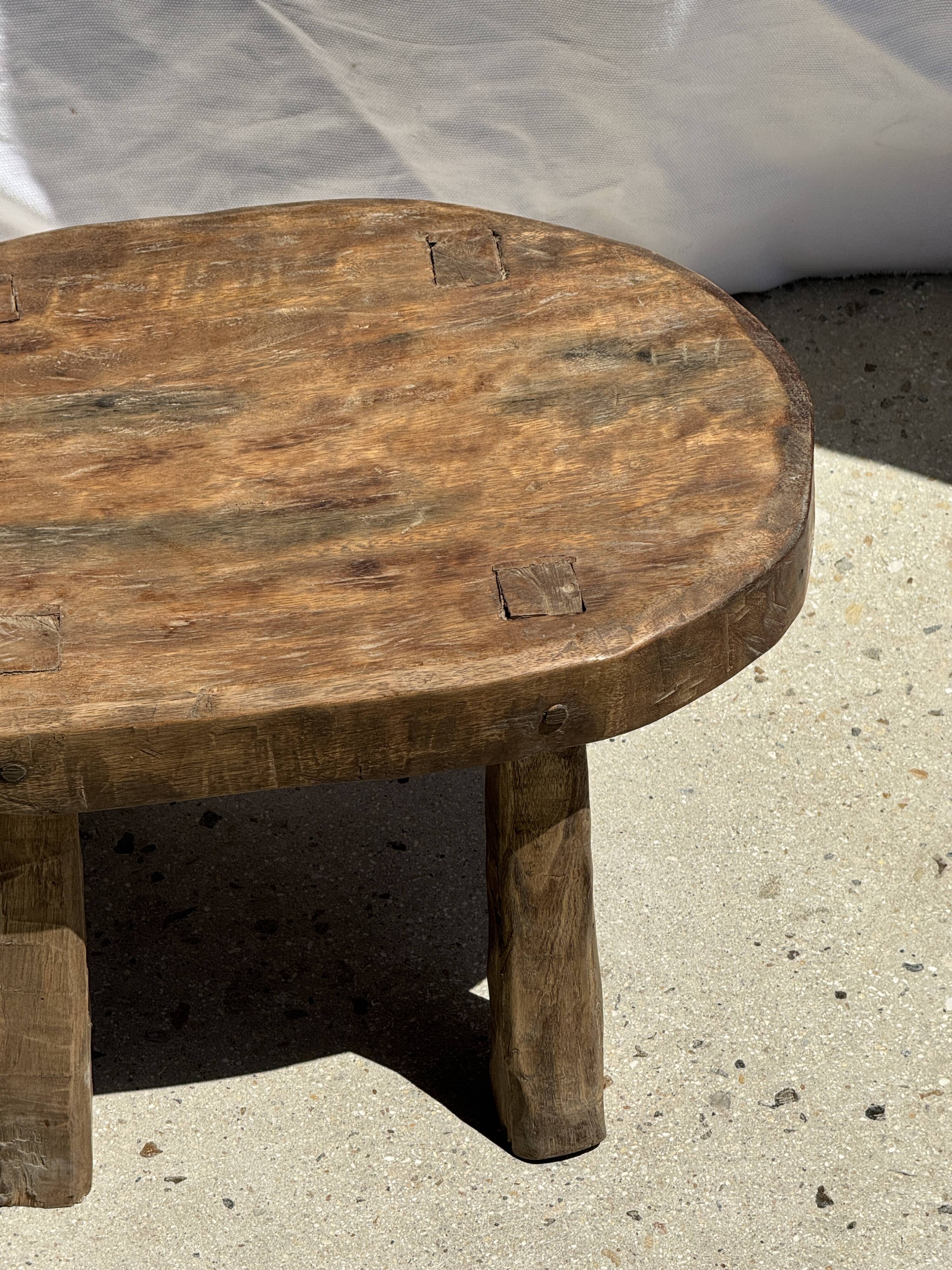 Small stool, oval solid teak side table with curved legs in wabi-sabi style.
