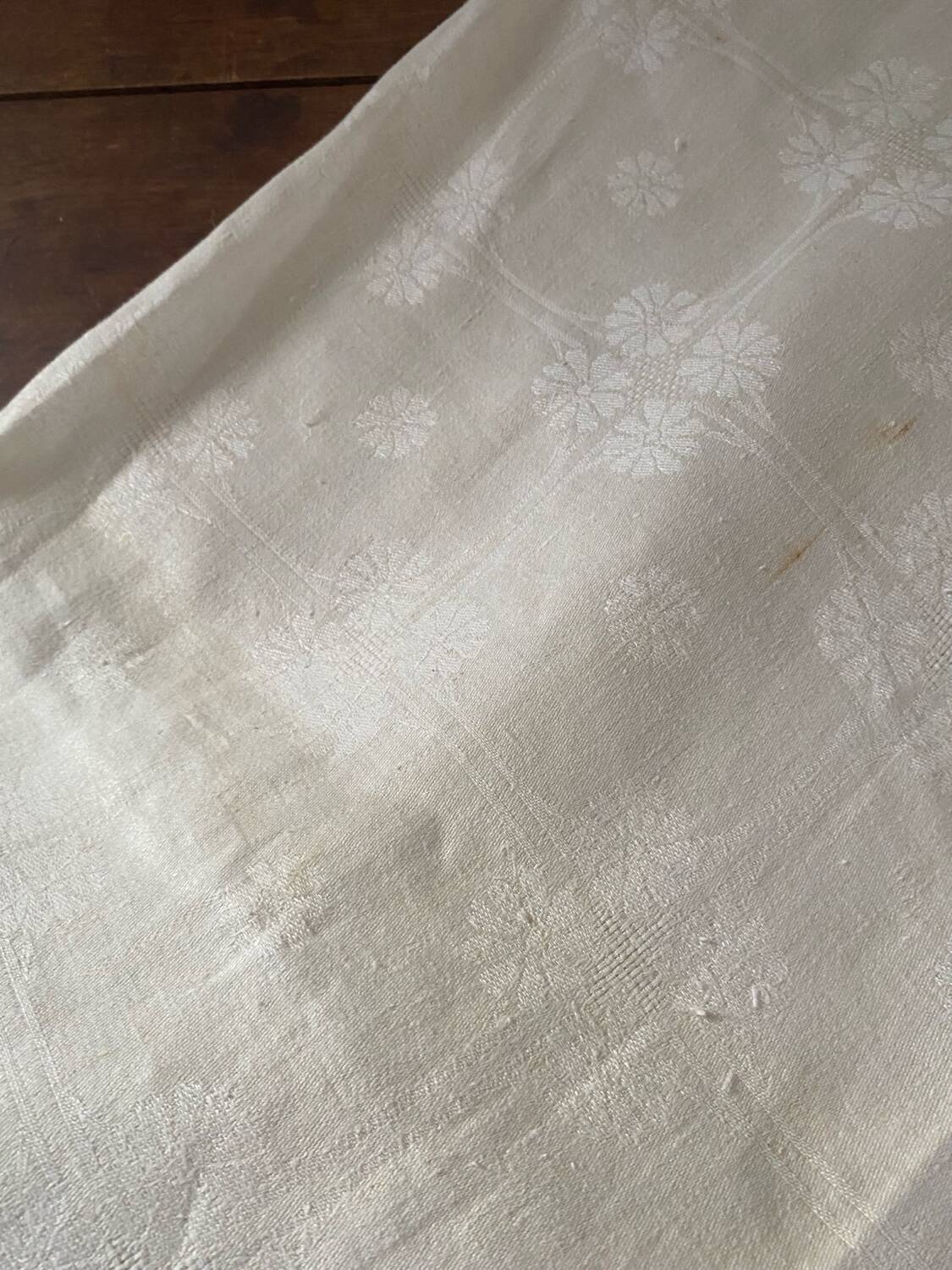 Damask tablecloth with a floral pattern and a central embroidered monogram.