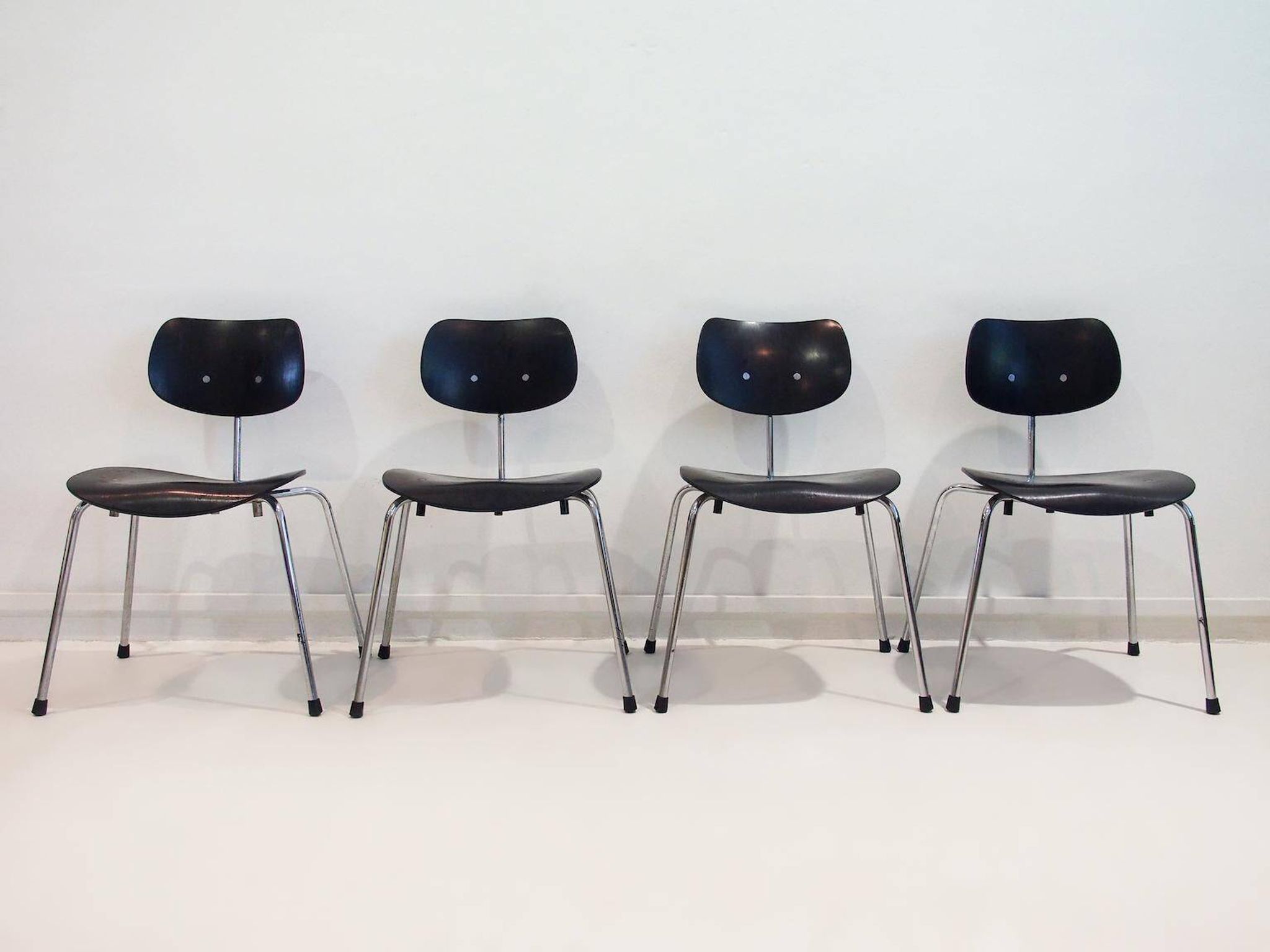 Set of four Egon Eiermann model SE 68 chairs in black lacquered plywood and steel.