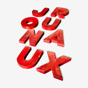 Lettres d'enseigne en zinc rouge formant le mot JOURNAUX