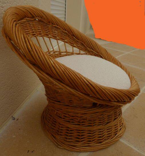 Wicker armchair with a high back and its boucle fabric cushion.