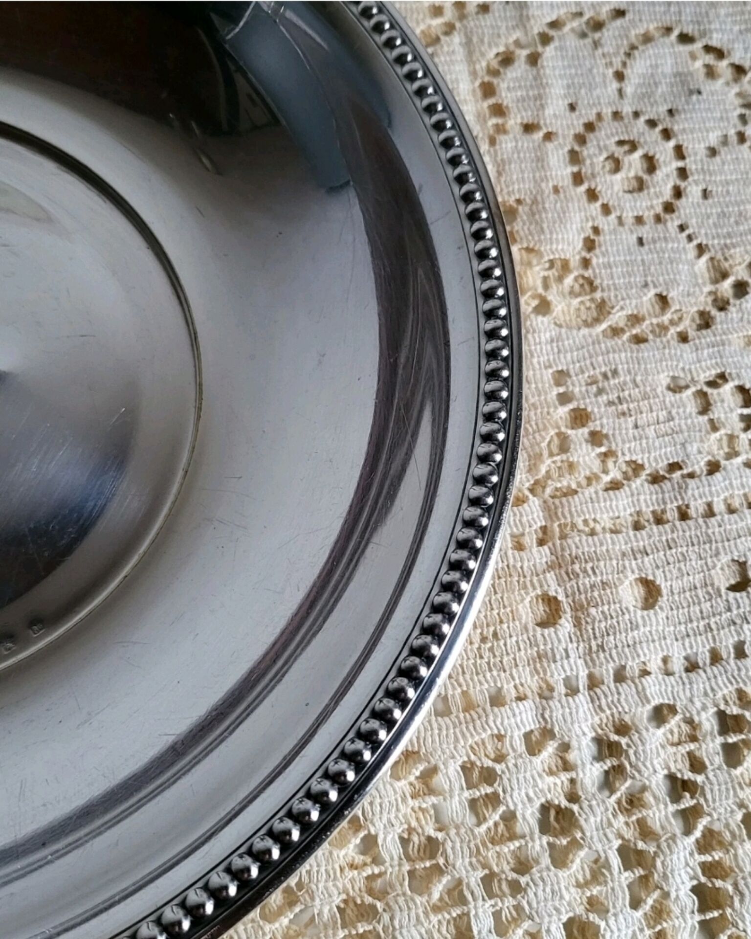 Shallow round metal plate with pearl row decoration.