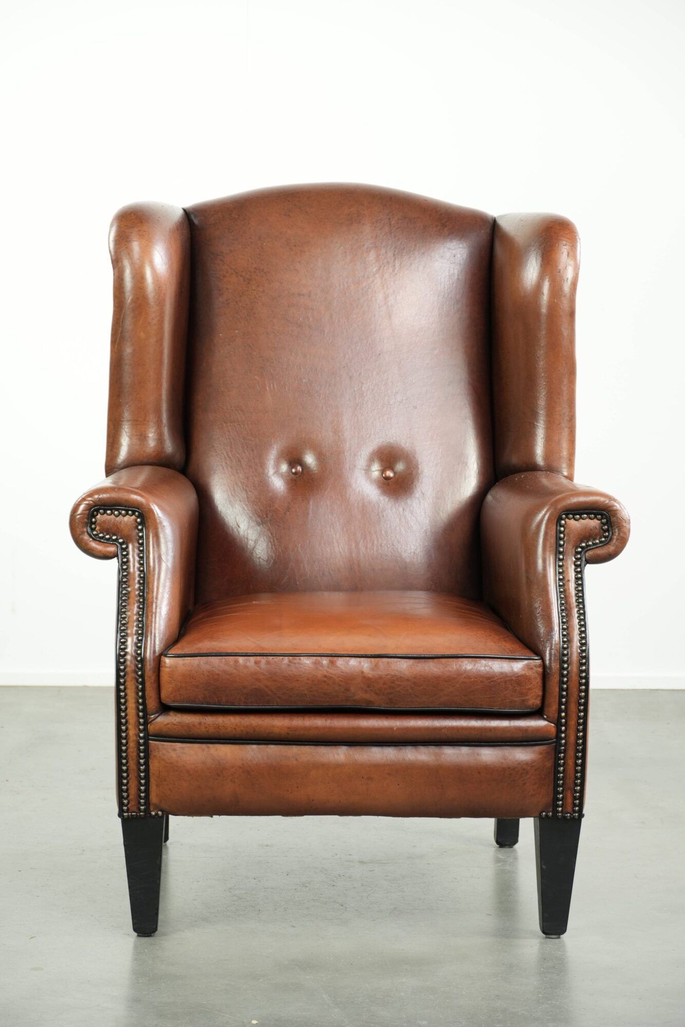Sheepskin wingback armchair finished with black piping and a correct seat