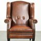 Sheepskin wingback armchair finished with black piping and a correct seat