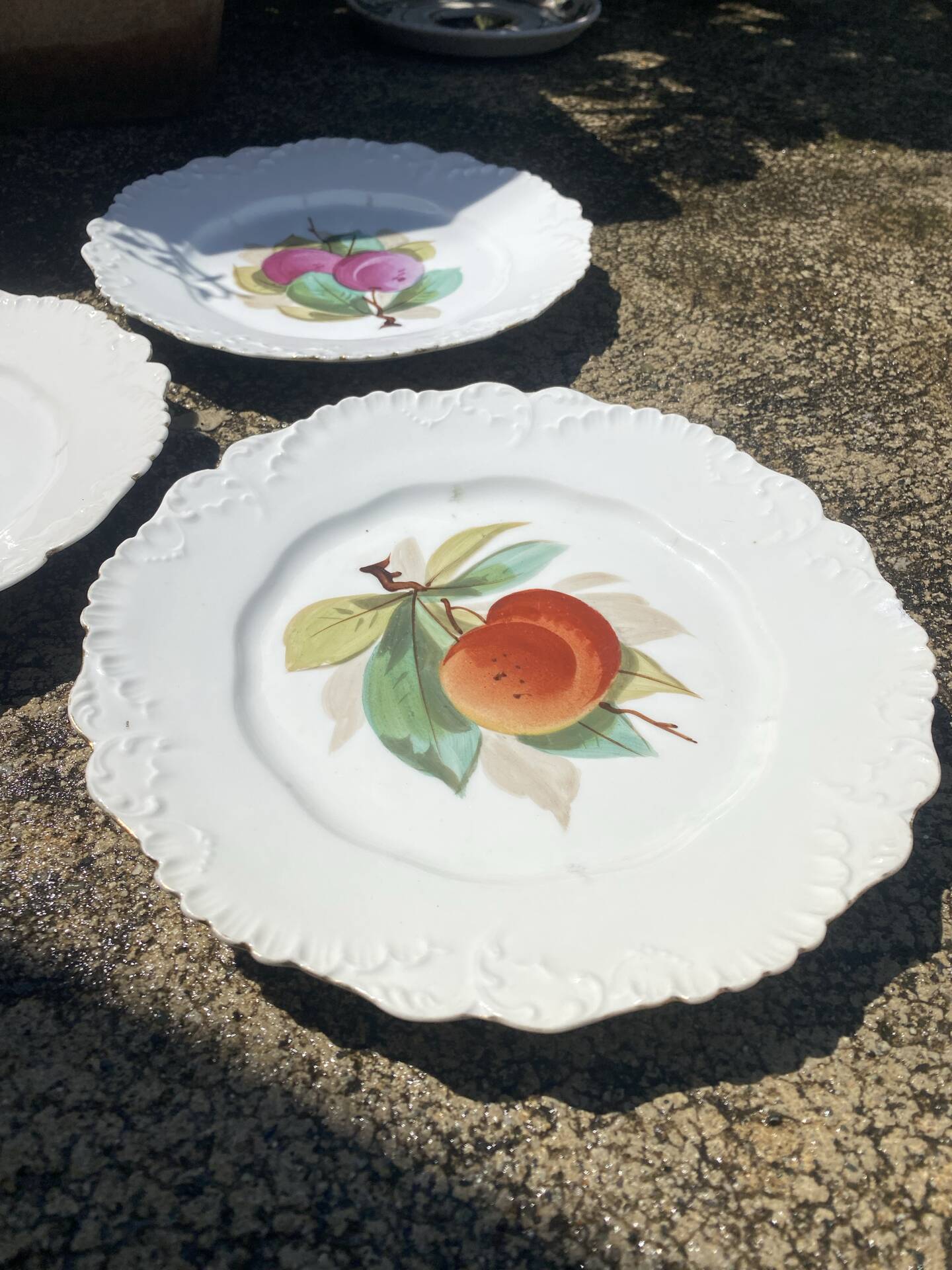 Antique plates from the late 19th century with scalloped edges and fruit decoration.