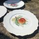 Antique plates from the late 19th century with scalloped edges and fruit decoration.