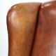 Large sheepskin wingback chair with black piping and decorative nails