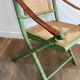 Paire de chaises safari pliantes façon faux-bambou patiné, dossiers et assises cannées et repose-bras en cuir