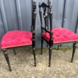 Pair of black lacquered chairs with purple tufted upholstery.