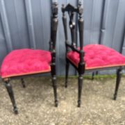 Pair of black lacquered chairs with purple tufted upholstery.