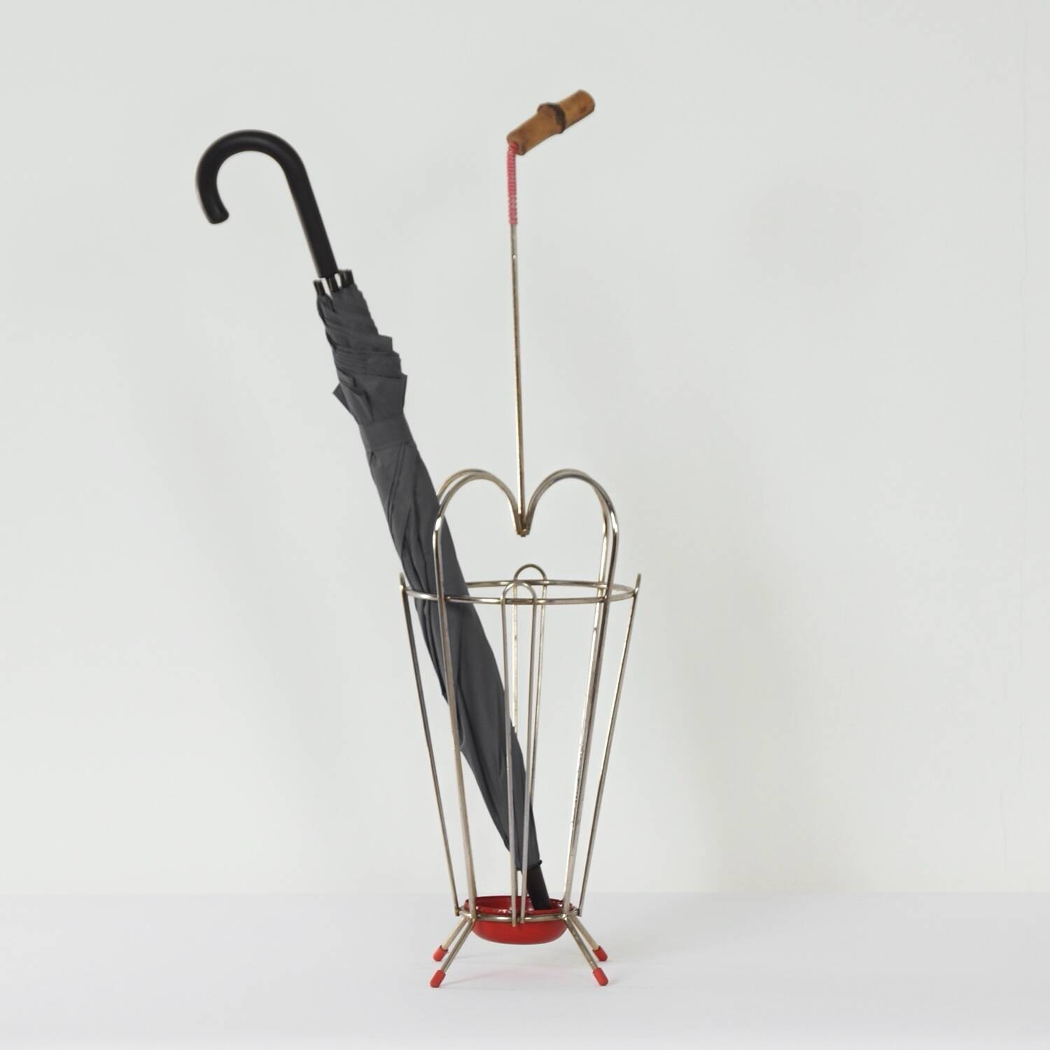 VINTAGE UMBRELLA STAND OF CURVED METAL, RED DETAILS AND A BAMBOO HANDLE, 1950S