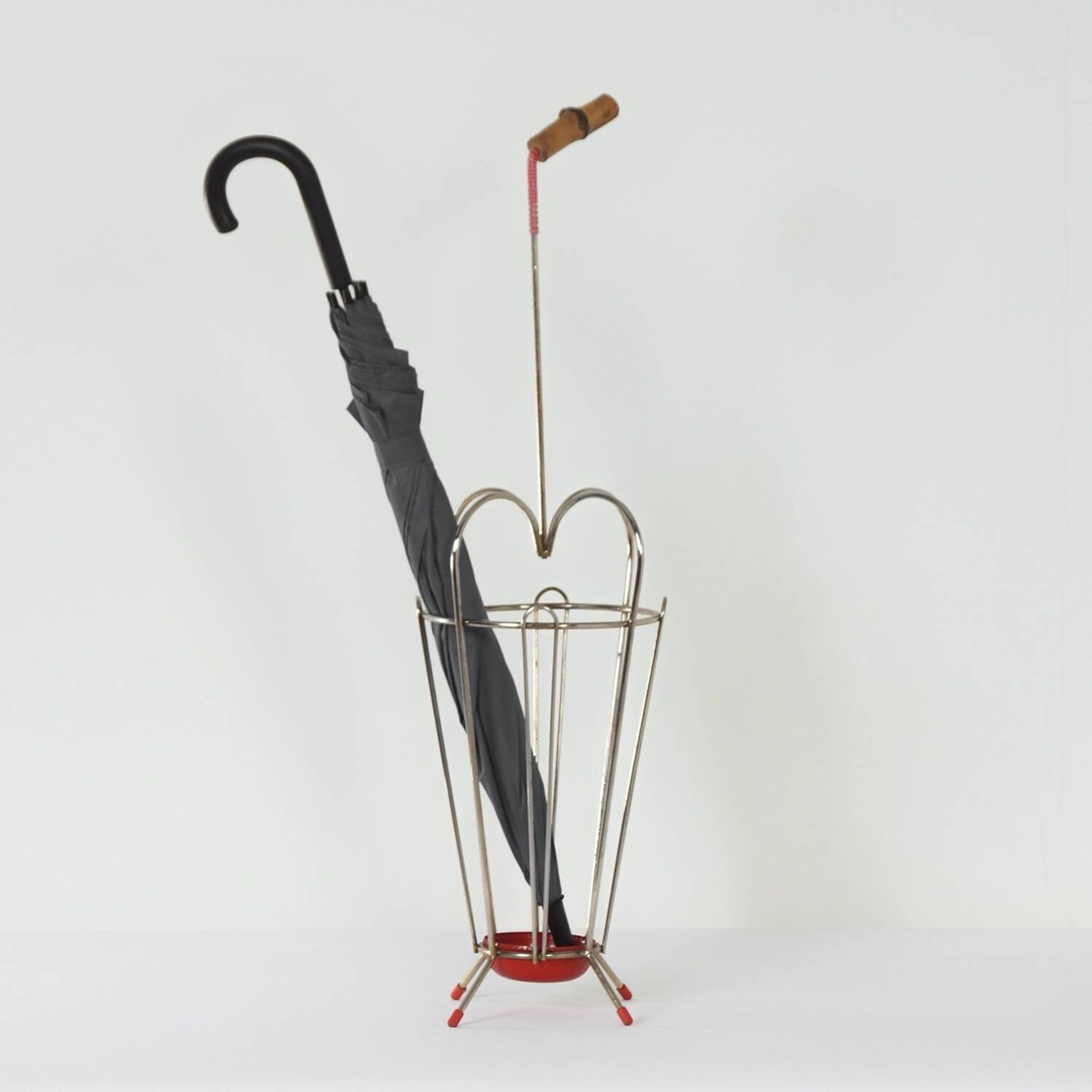 VINTAGE UMBRELLA STAND OF CURVED METAL, RED DETAILS AND A BAMBOO HANDLE, 1950S