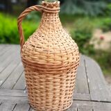Old demijohn with handle covered with wicker