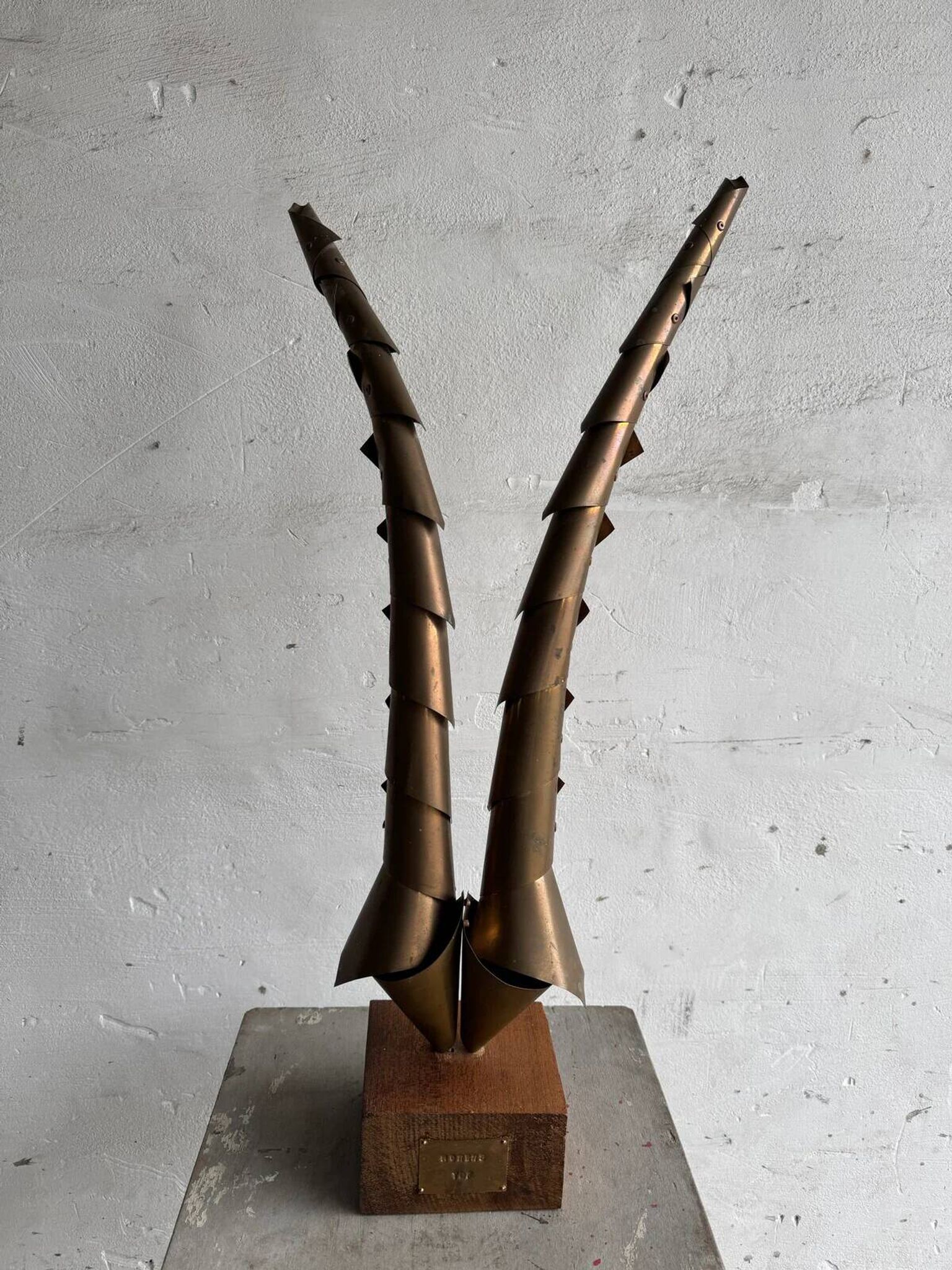 Golden brass sculptural horns on wooden base — modern metal art sculpture, 68.5 cm high