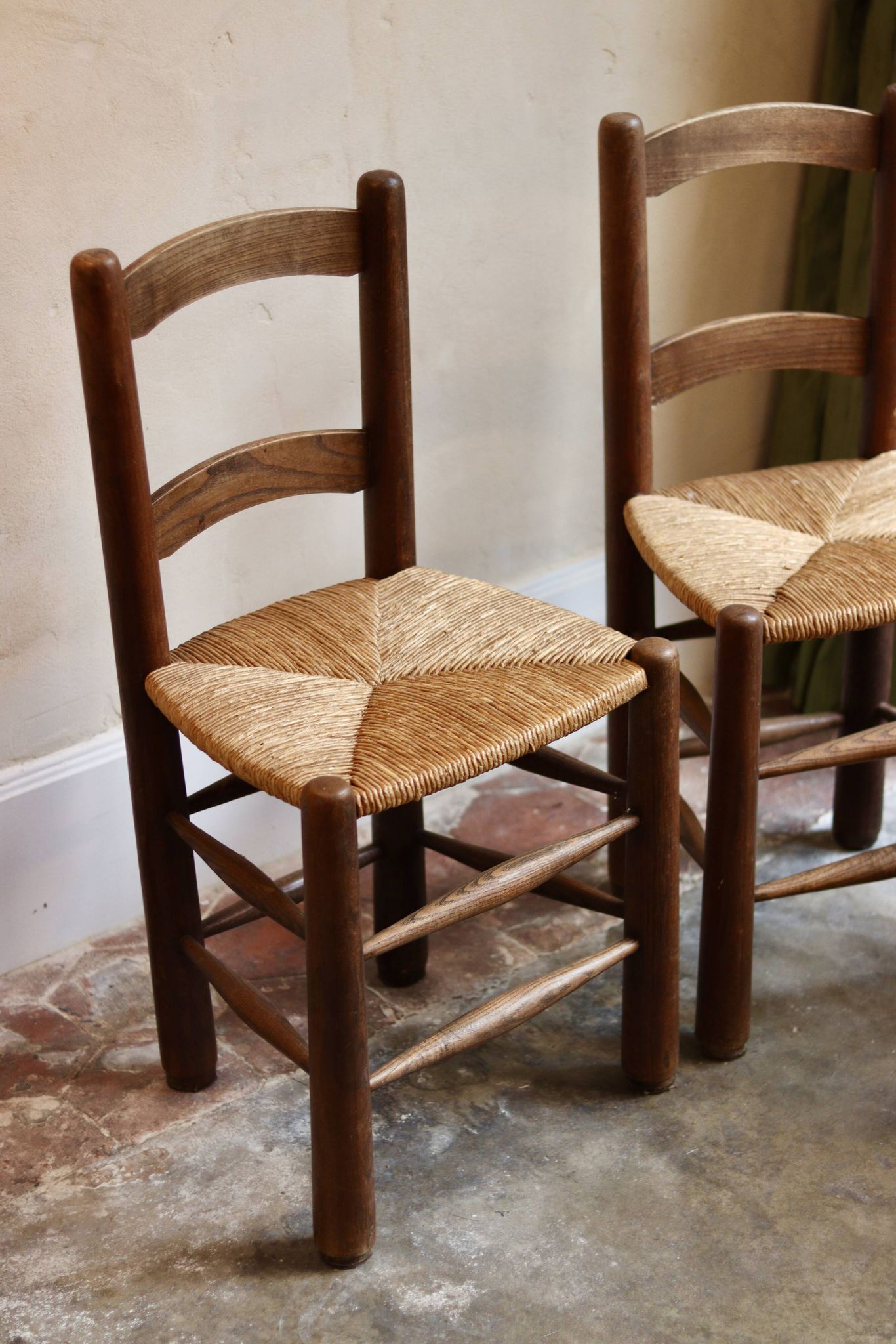 Pair of wooden chairs with woven straw seats.
