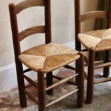 Pair of wooden chairs with woven straw seats.