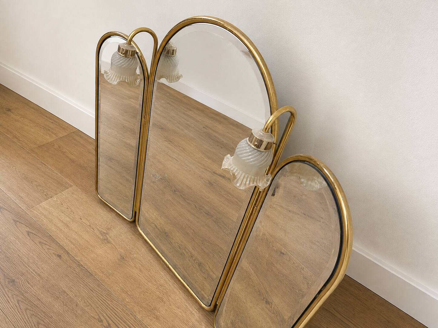 Vintage triptych mirror in brass with wall lights.