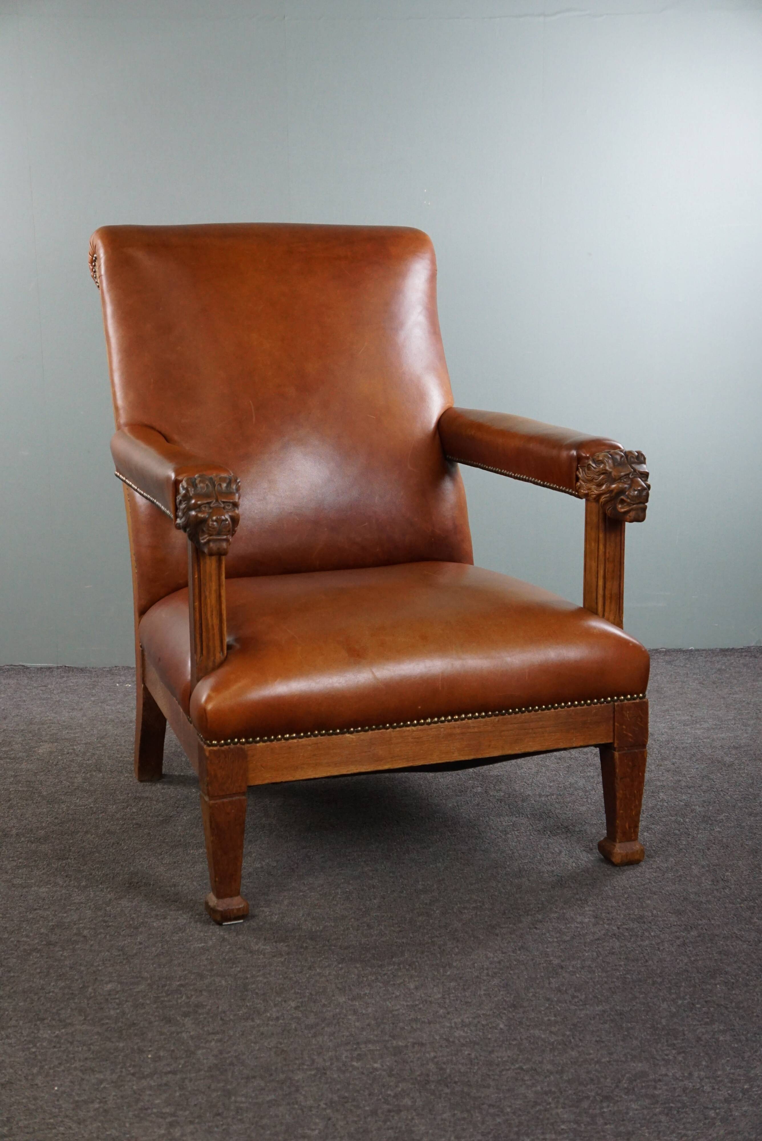 Armchair with lion heads reupholstered in cognac-colored cowhide leather