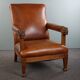 Armchair with lion heads reupholstered in cognac-colored cowhide leather