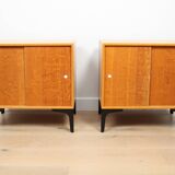 A pair of vintage mid-century bedside tables with oak sliding doors