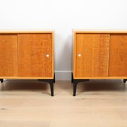 A pair of vintage mid-century bedside tables with oak sliding doors