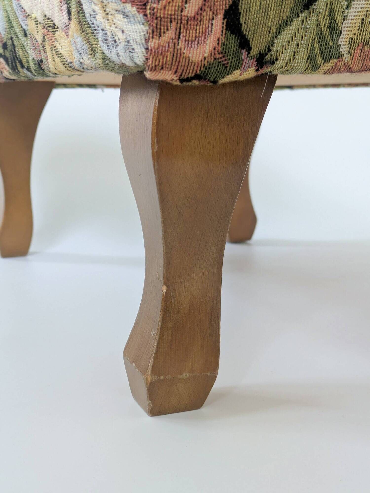 Large vintage upholstered footstool with curved legs.