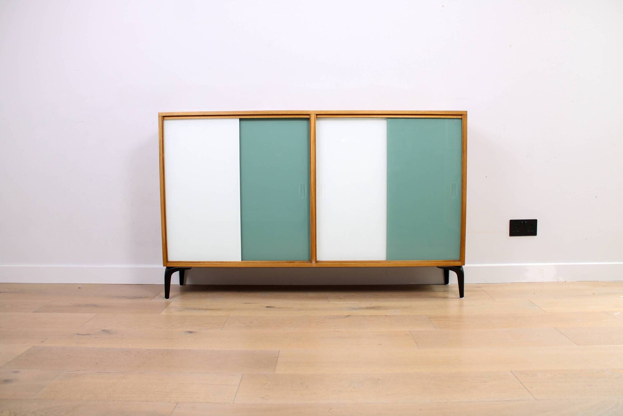 A vintage mid-century bookshelf/sideboard with green and white sliding door