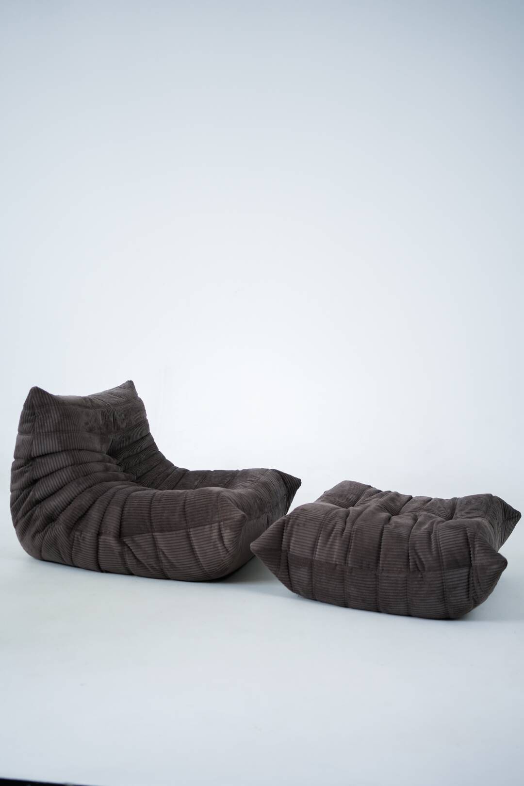 Ensemble de chaise et pouf Togo en velours côtelé marron.
